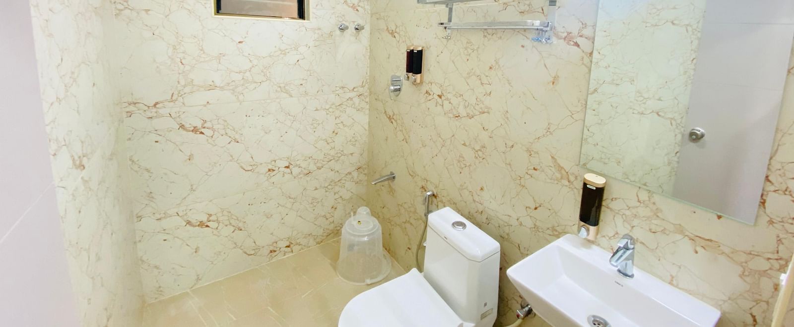 Modern bathroom with marble finish, shower area, and essentials at Hotel Sahara Tree.