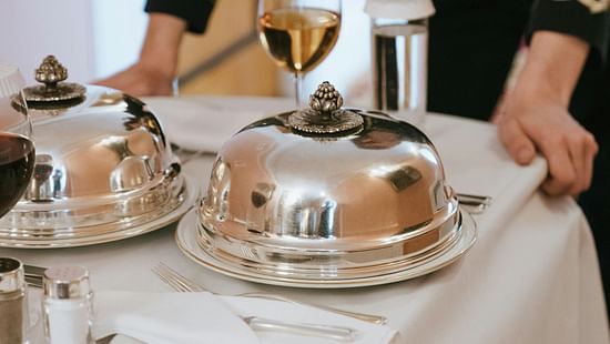 Picture of a waiter with a trolley table, a few dishes on table