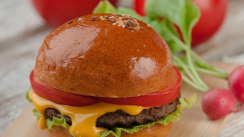 A delicious looking burger served with a side of tomatoes