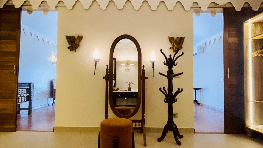 Vana Junior Suite at Surpura Bagh featuring full size vanity mirror and a stool chair in front of it and a wooden piece which holds accessories.