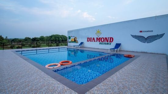 A pool at VITS Select Diamond Resort, Sasan Gir, with two lifebuoys. A mural of a lion and the hotel name are on the wall.