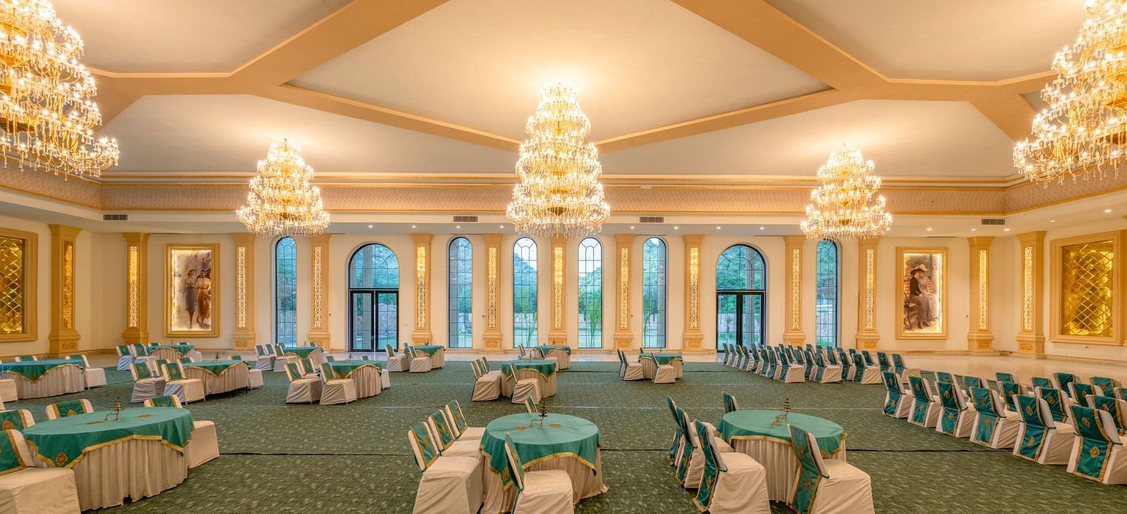 Side view of a banquet hall featuring round tables with chairs and chandeliers elegantly hanging from the ceiling at Valley by Grassfield.