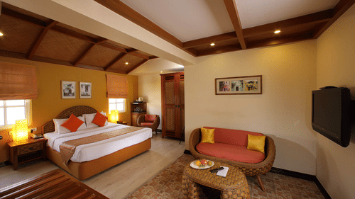 A spacious bedroom with a king bed and a sitting area at The Richmond Puducherry.