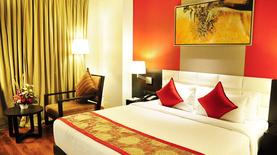 A brightly lit Executive Room featuring a double bed along with a medium size painting hung above it - Senses Hotel