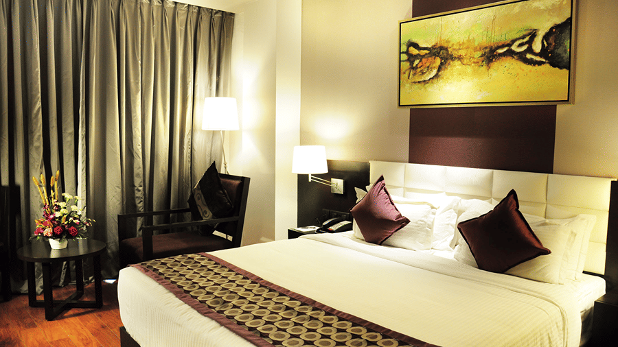 A bedroom with modern interiors featuring a double bed along with a common seating area in the corner of the Executive Room - Senses Hotel