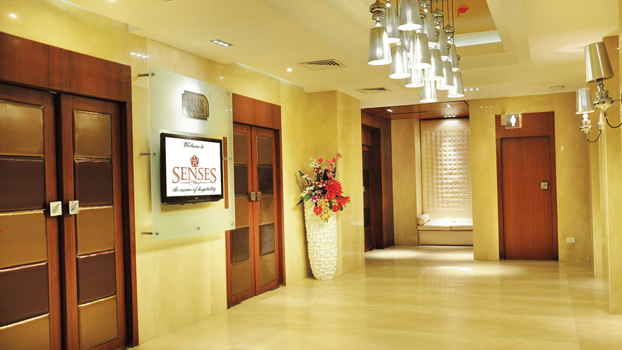 Corner view shot of the corridor at Senses Hotel featuring two huge wooden doors and a television screen in the middle.