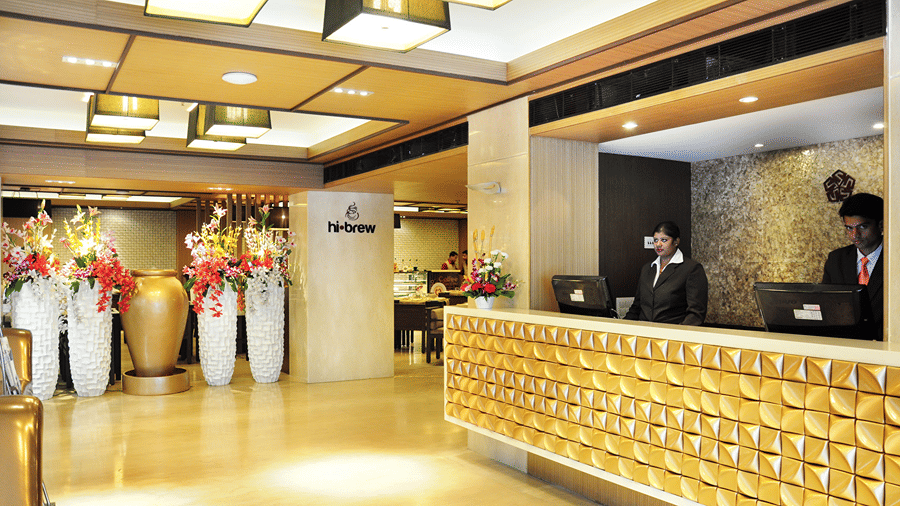 A brightly lit reception area with two staff members standing behind the reception desk at Senses Hotel.