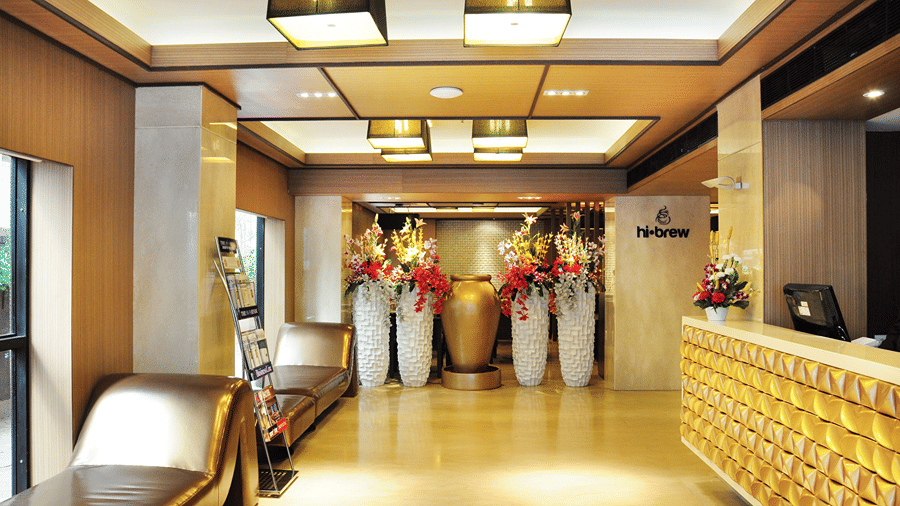 Full view shot of the lobby at Senses Hotel in Kolkata with four huge flower vases kept at the far end of the lobby.