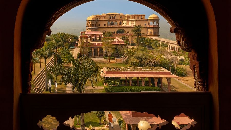 View of Rani Mahal from Hawa Mahal arched window  revealing the multi-tiered structure and surrounding landscape at Tijara Fort-Palace - 19th Century, Alwar.