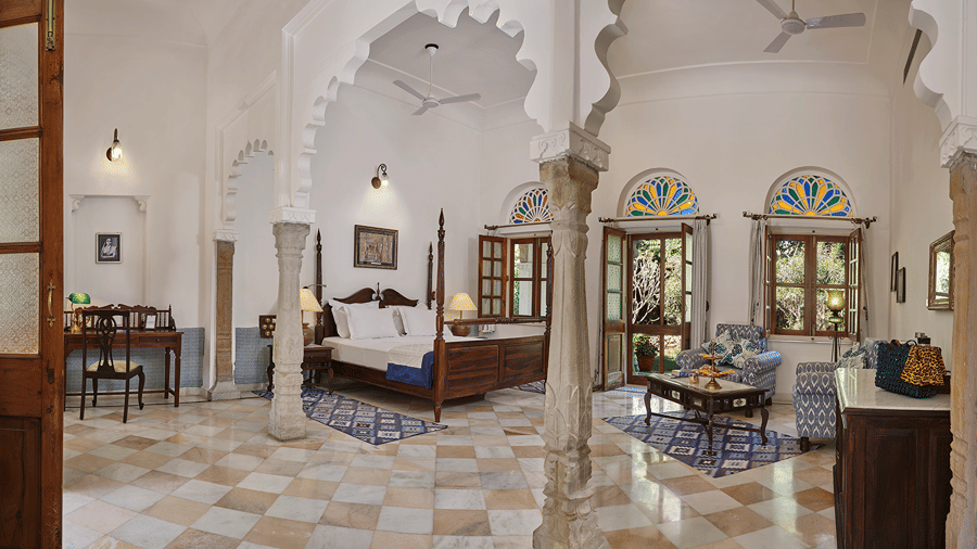 Heritage-style suite with stone archways, carved pillars, and a 4-poster bed at Dev Shree, Deogarh.