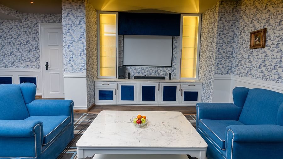 An image of the living room with coffee table, sofas and a wall-mounted projector - The Manor Luxury Hotel, Shimla