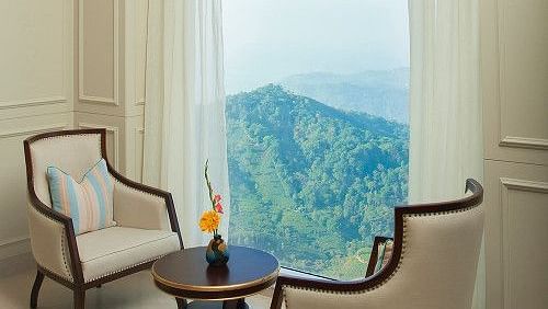 Two-seater dining with a mountain view deom windows at Fragrant Nature Munnar