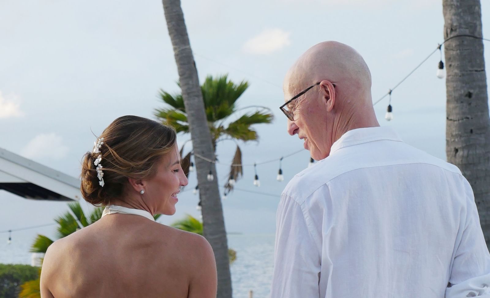 A back-shot of a couple walking down a path lined by palm trees with a at Casa Morada.