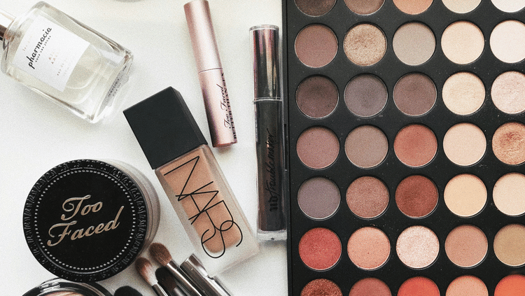 Beauty cosmetic products arranged on a table, featuring brushes and a vibrant color palette