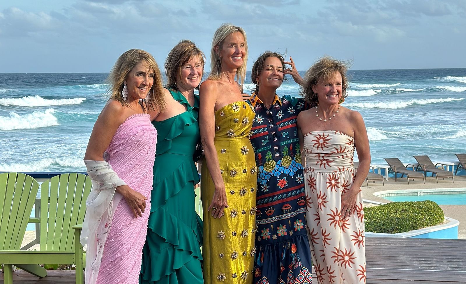 Four women posing on a deck near the beach side. 