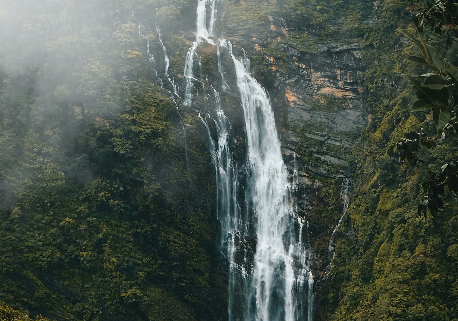 Landscape photograph of a tall waterfall flowing down a rocky cliff.