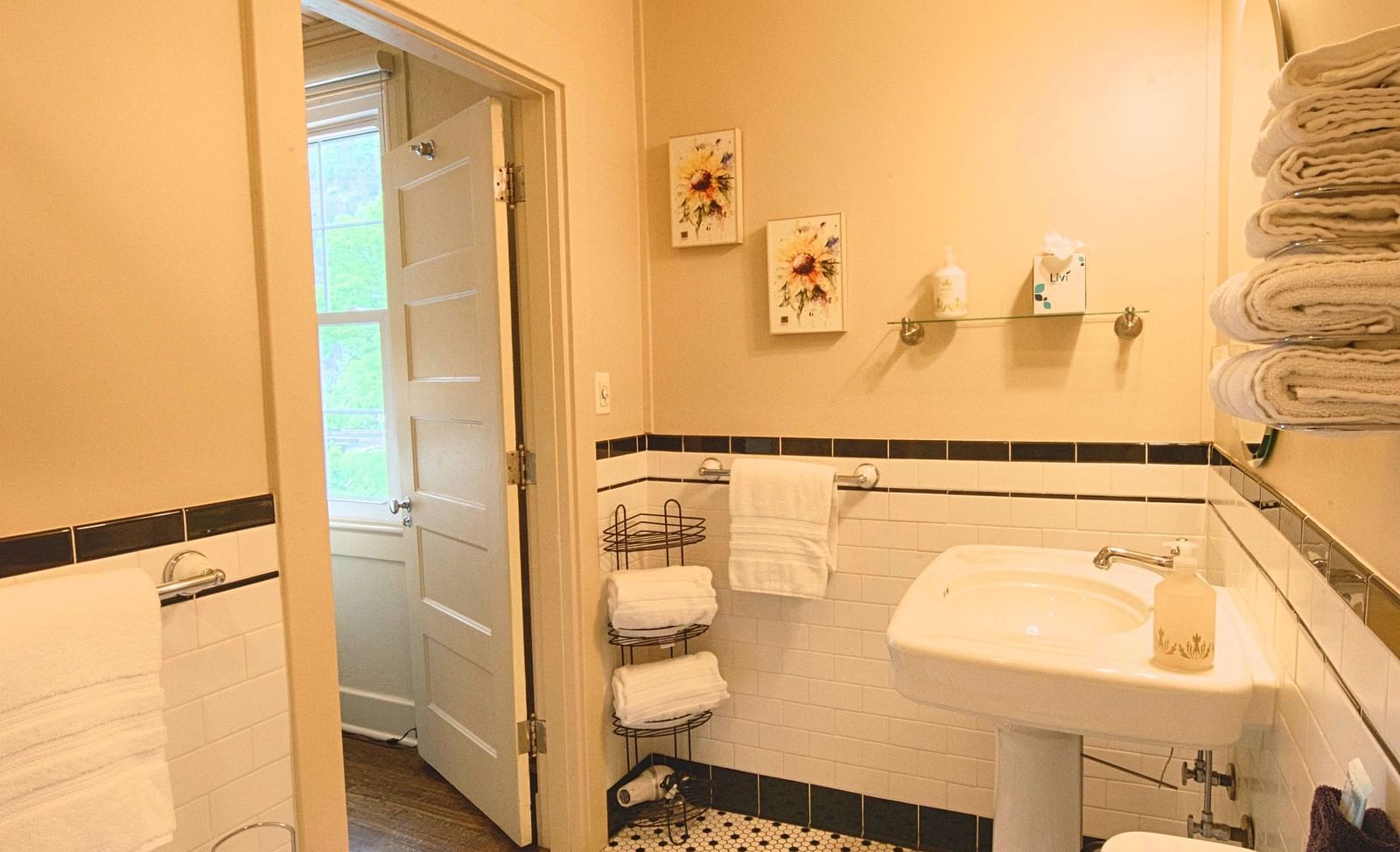 full view image of a compact bathroom with all necessary linens and toiletries and a door opening to the room - Historic Tapoco Lodge