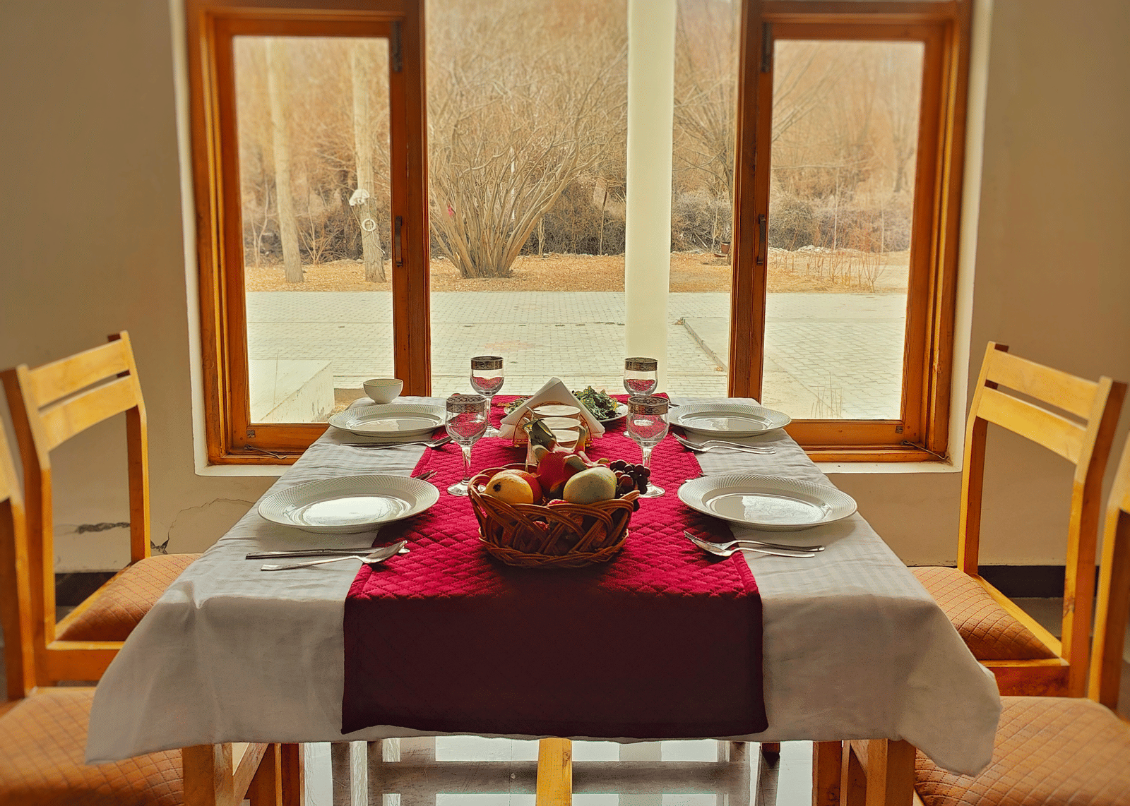 A symmetrical view of a dining table prepared for guests, positioned to look out over the grounds at Indus Serenity Retreat.
