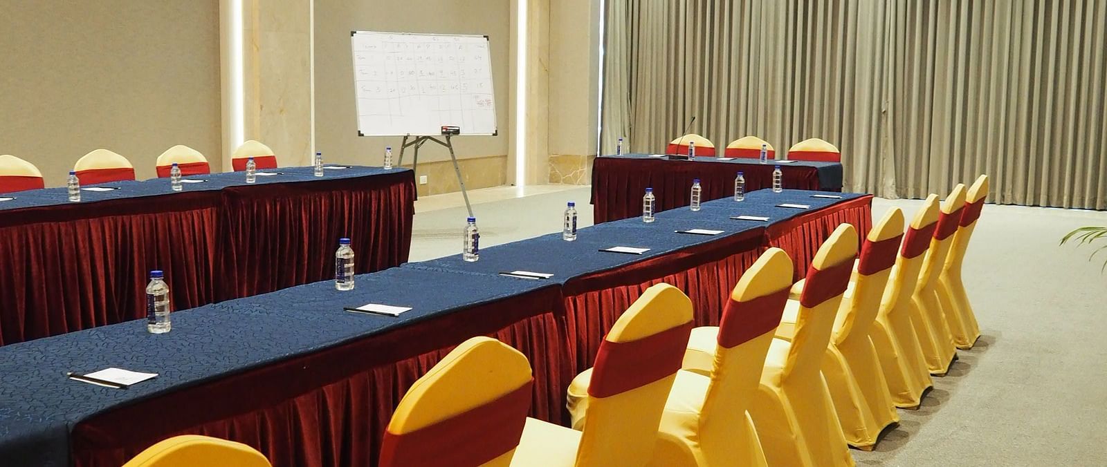 A long table with yellow chairs in a brightly lit, spacious conference hall - Club Charholi, Pune 