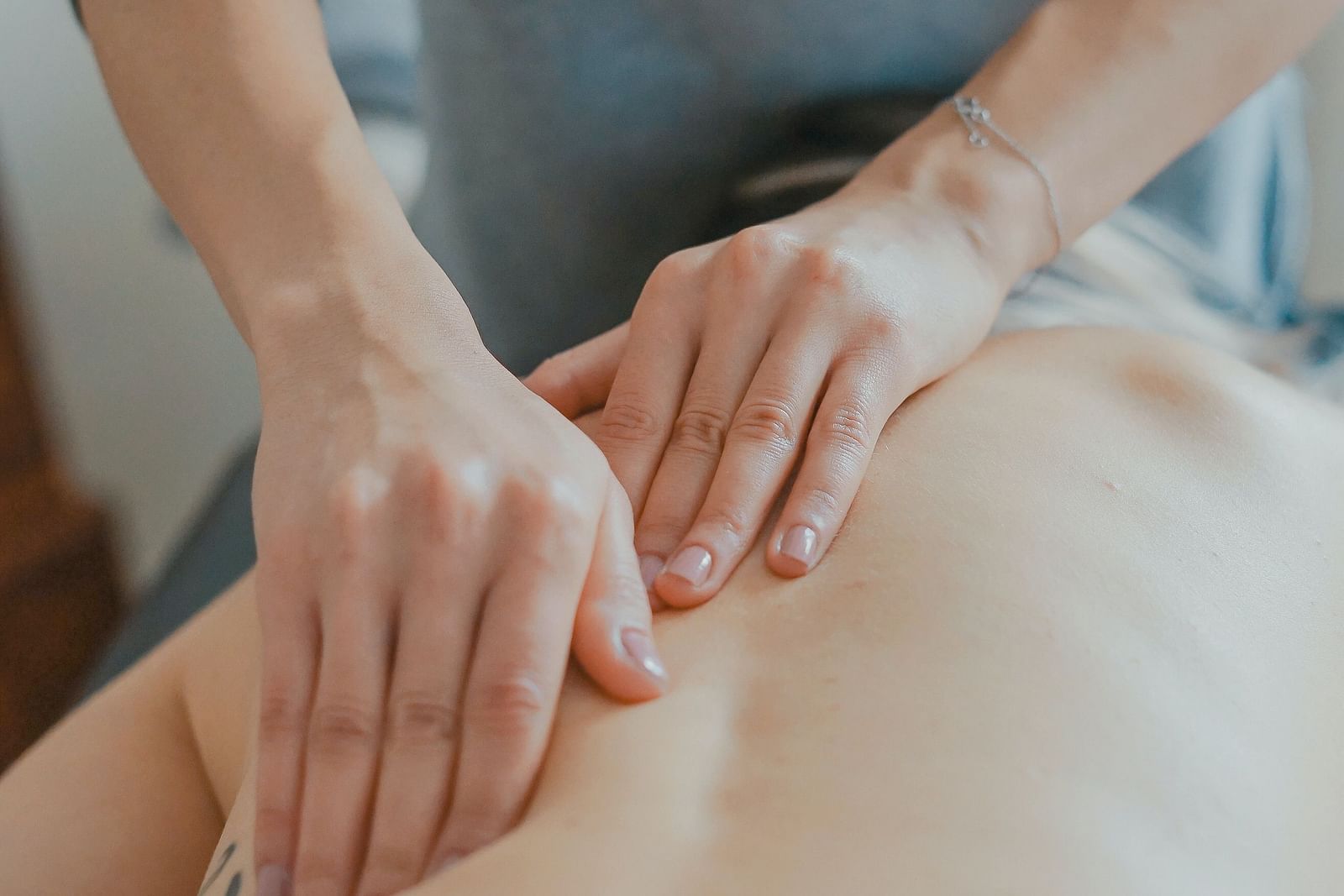 two hands massaging the back of a person at a spa
