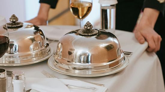 Picture of a waiter with a trolley table, a few dishes on table