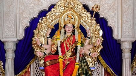An overview of the hindu deity Goddess Durga's idol kept inside a temple with a garland on it.