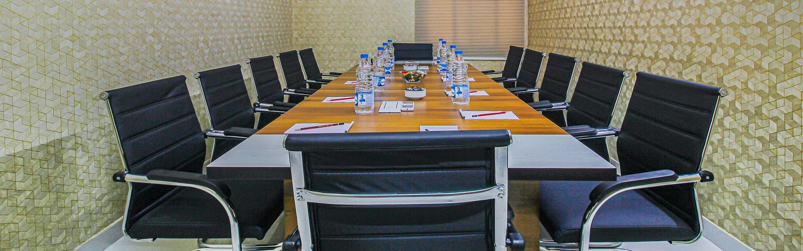 A conference room with a professional setting, featuring a large meeting table with water bottles and notepads for attendees.