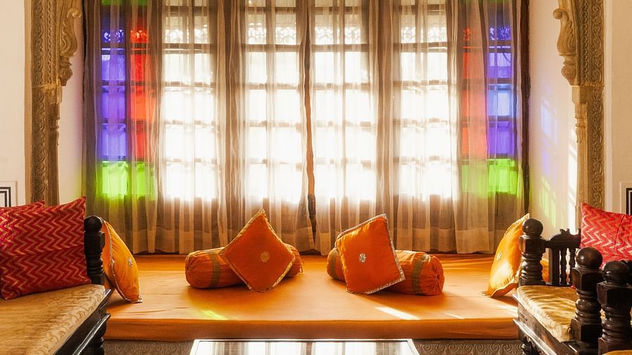 A cosy alcove at Fort Barli, featuring stained glass windows, plush cushions, and a low table, creates a vibrant and inviting seating area.