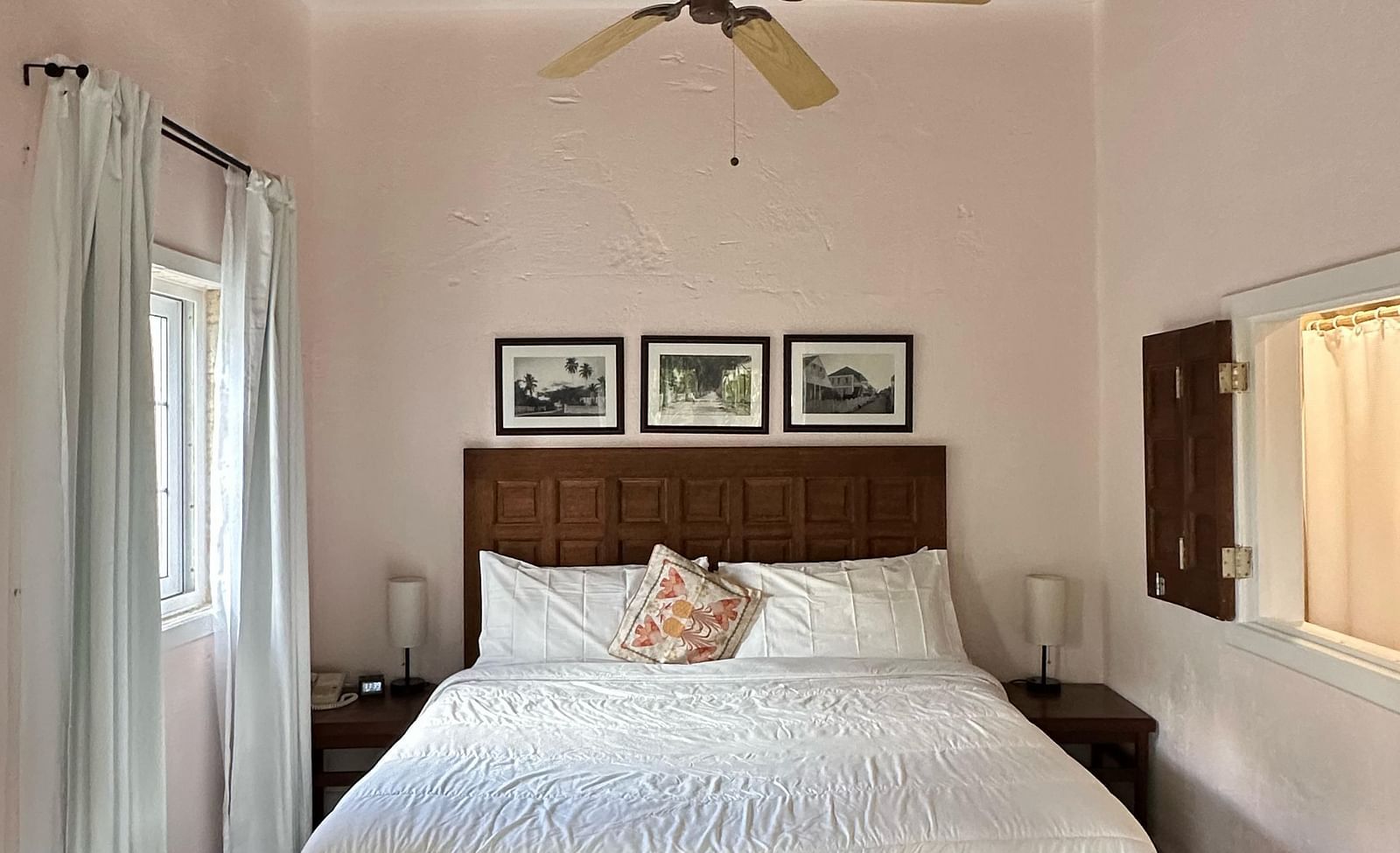 A bedroom with a bed covered in white linens and dark wooden floors | A Stone's Throw Away