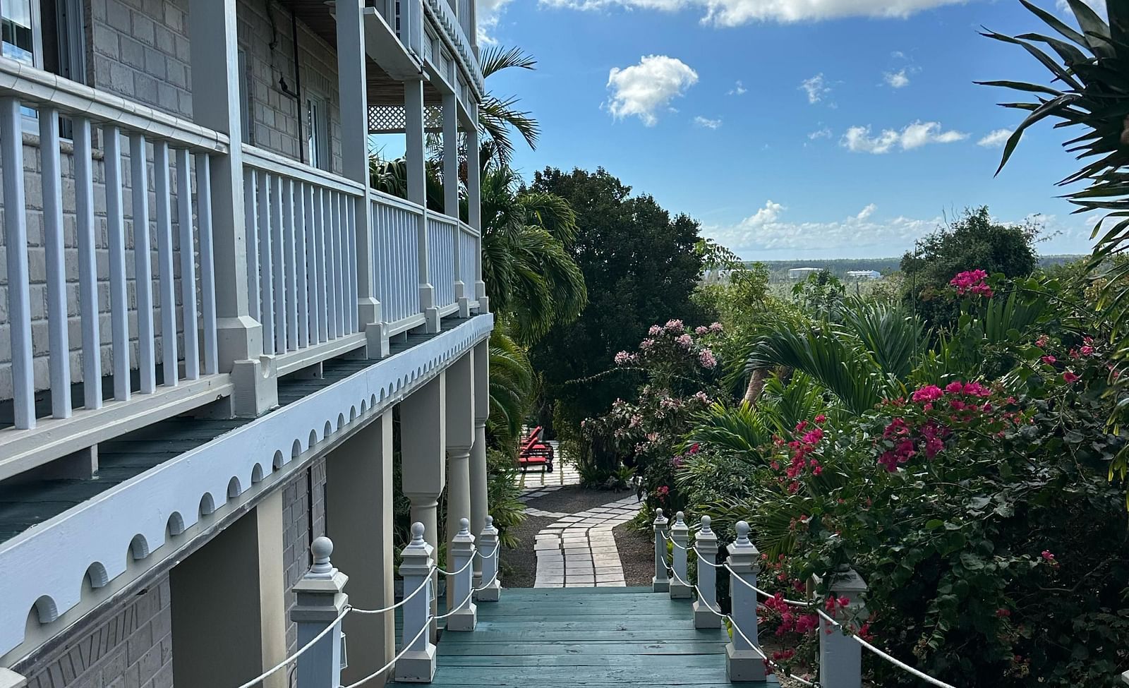 Exterior corridor with white railings and garden path below | A Stone's Throw Away