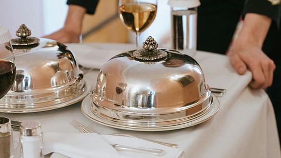 Picture of a waiter with a trolley table, a few dishes on table
