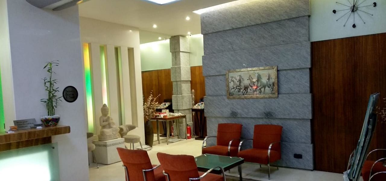 Reception area with a comfortable chairs around a glass table at Regency Hotel, Mumbai.