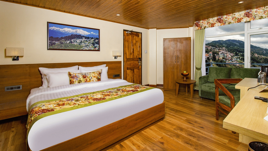 Our room featuring a balcony, warm wooden interiors, a king size bed, seating area, and spacious layout | Mount Lungta - A Darjeeling Hotel with Balcony