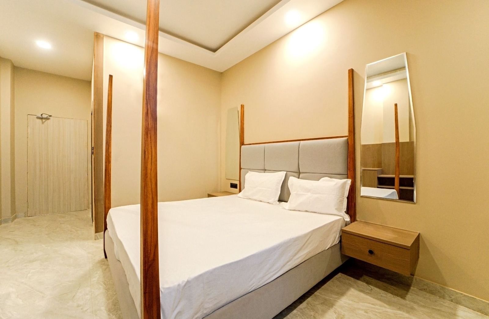 A bedroom at Grassfield Riveria Resort, Jaipur, with a four-poster bed, minimalist decor, and a private bathroom.