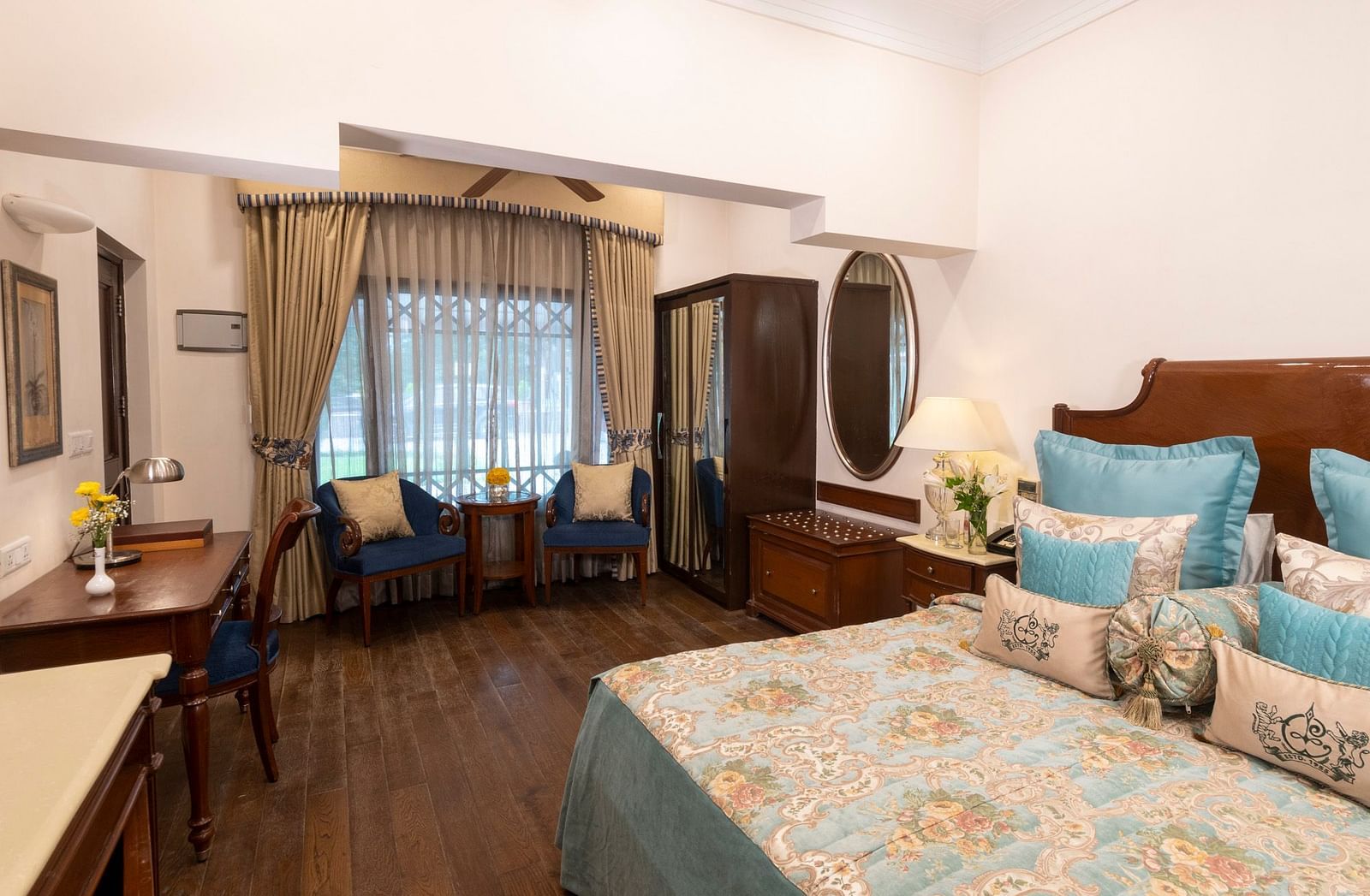 view of the deluxe room with king sized bed with comfortable chairs and a workspace at the Claridges Nabha Residence, Mussoorie