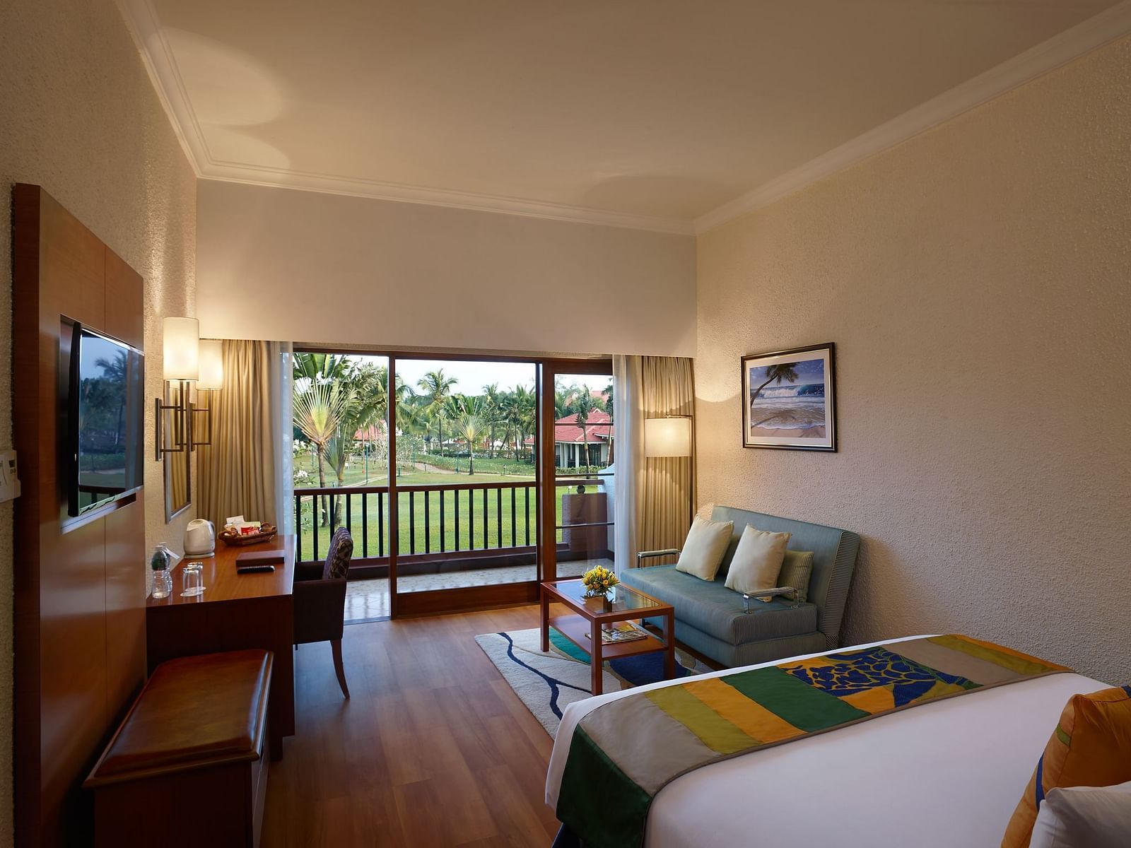 a double bed with a sofa and a tv in view inside Garden View room - Caravela Beach Resort Goa 