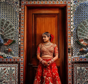 An image of a women in a wedding outfit standing in front of a closed wooden door