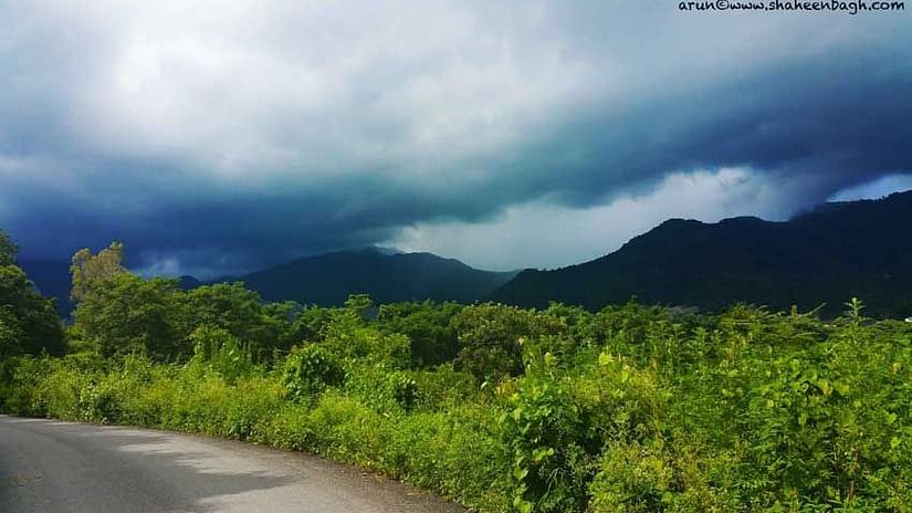 An overview of the outdoor area with hills and mist covering near Shaheen Bagh Resort, Dehradun.