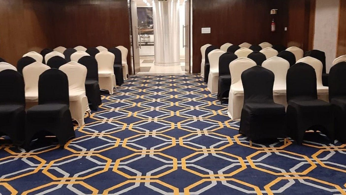 A well-arranged conference hall at the banquet hal, The Cunningham Hotel, featuring elegant black and white chairs, a vibrant geometric-patterned carpet, warm lighting, and a sophisticated ambience