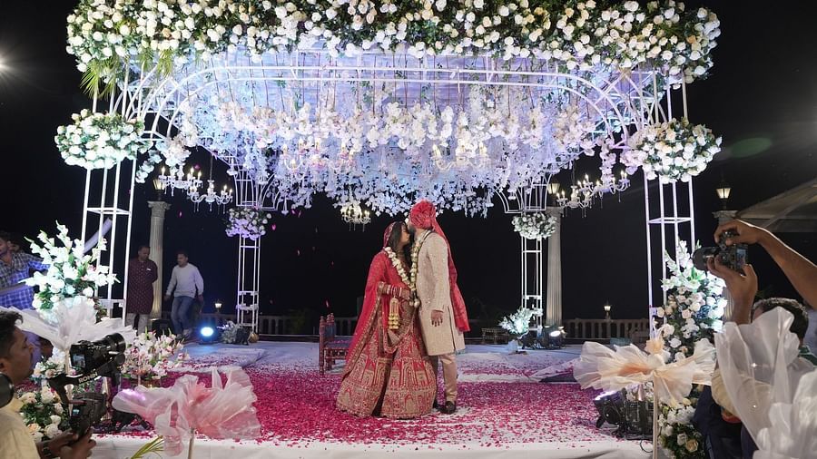 Groom giving a peck to his bride on her forehead on the stage which is decorated with flowers at The Grand Legacy Resort & Spa
