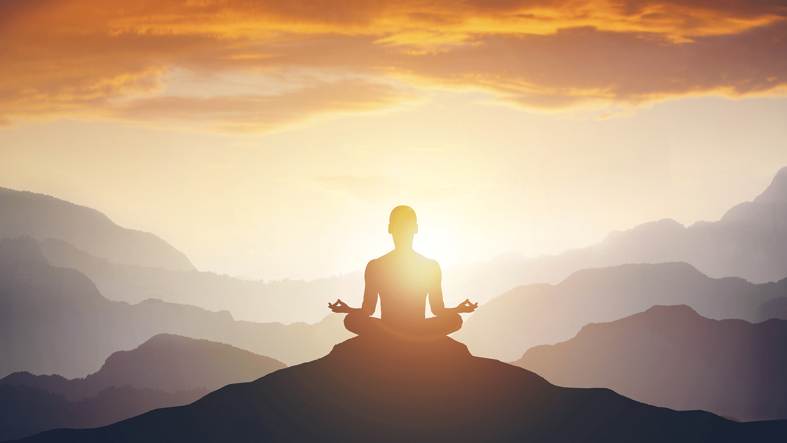 a silhouette of a person doing meditation on a hilltop with sun rays shining in the background