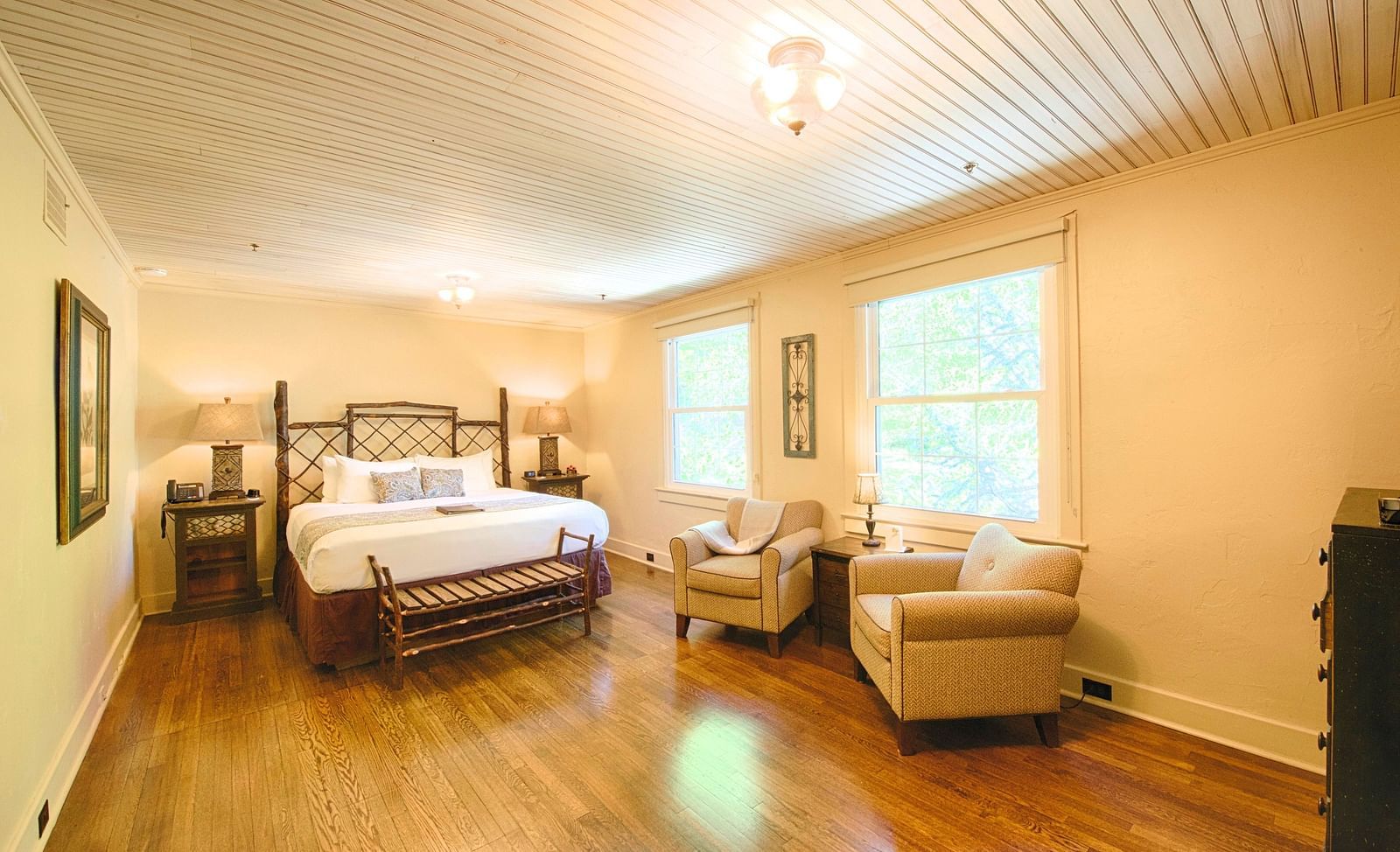 corner view image of a spacious bedroom featuring a common seating area along with a comfortable double bed - Historic Tapoco Lodge