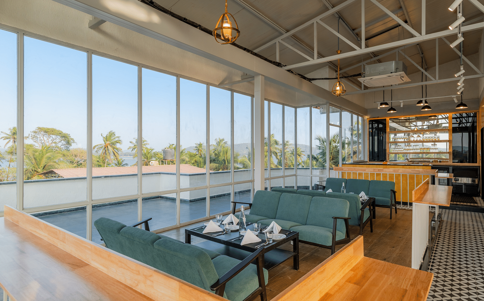 Spacious cafe interior with large windows and comfortable seating at Bedzzz Xclusiv Morjim, Goa