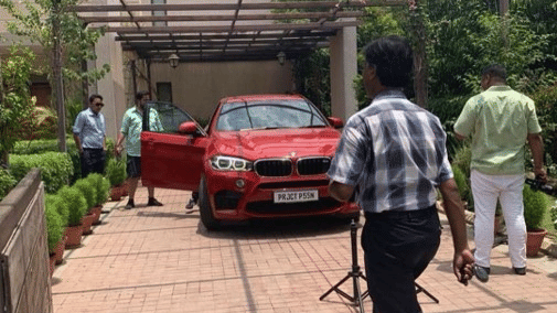 A red car parked with the door opened while people walking next to it - Karma Lakelands.