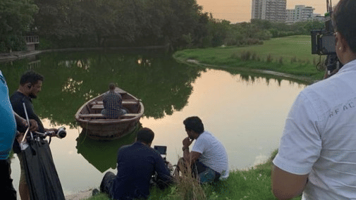 A lake surrounded by greenery while people are working for a photoshoot - Karma Lakelands, Gurgaon