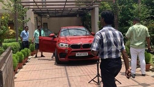 A red car parked with the door opened while people walking next to it - Karma Lakelands.