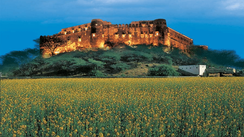 The facade of Hill Fort Kesroli Kesroli with grass at the forefront and blue sky in the background.