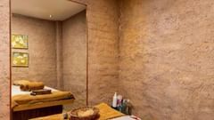 Massage room with a single treatment bed and towels at Golden Tulip, Udaipur.
