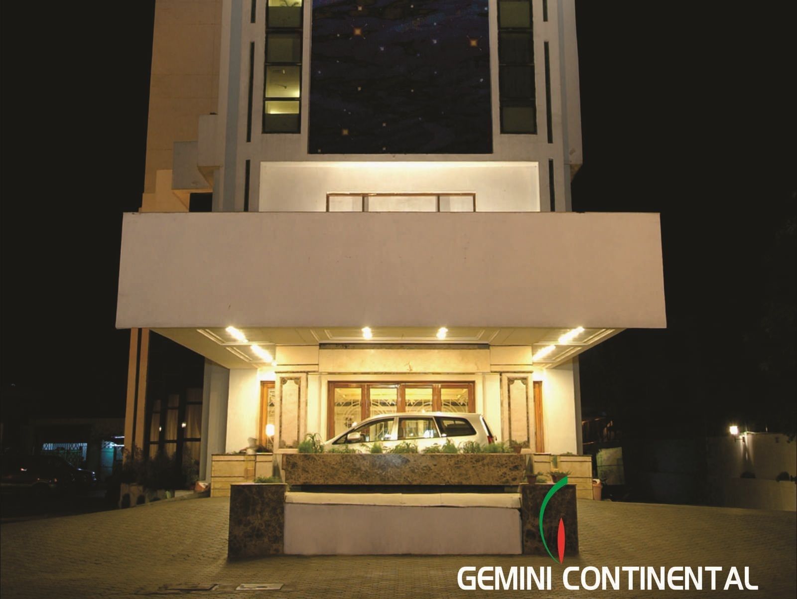 The facade view of a modern hotel building illuminated with lights in the ground floor  at night time.