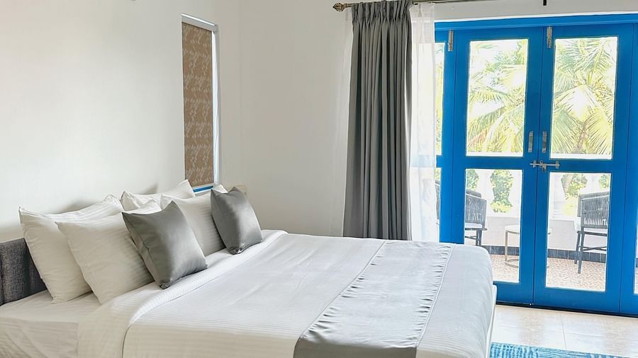 A king bed with blue door to the balcony inside one of the rooms at Azalea By Stone Wood Premier, Orlim